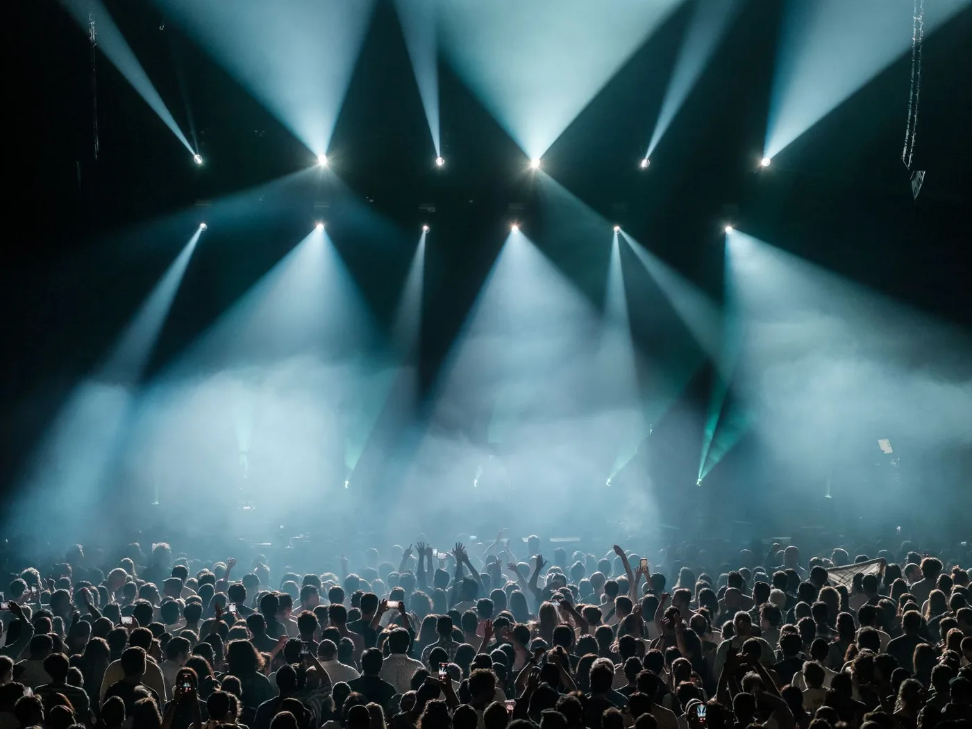 A large concert crowd beneath blue stage lights