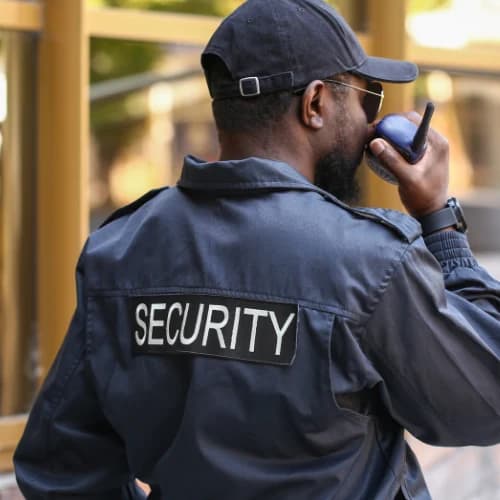 A security officer speaking into a two-way radio